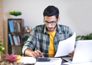 Man sitting at table calculating bills.